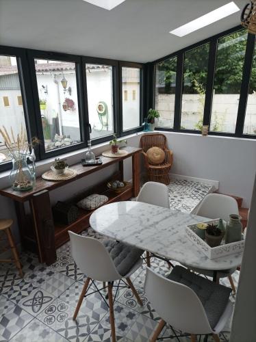 une salle à manger avec une table, des chaises et des fenêtres dans l'établissement House 10 minutes' walk to 24h, à La Celle-sous-Gouzon