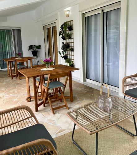 a living room with tables and chairs and windows at La Villa Mirabelle in Saint-Benoît
