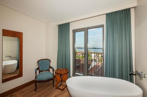 a bathroom with a tub and a chair and a window at Triton Hotel in Istanbul