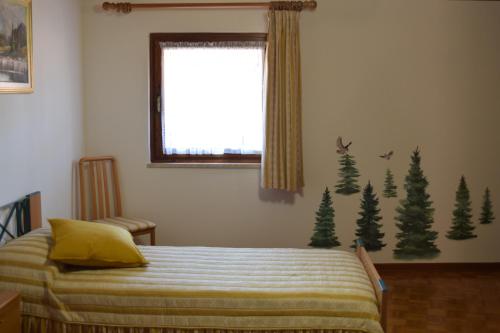 a bedroom with a bed with christmas trees on the wall at Nel borgo di Zia Alma in Cormòns