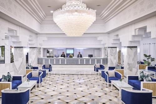 a lobby with blue chairs and a chandelier at Les Quatre Saisons Ex Baya Beach in Djerba