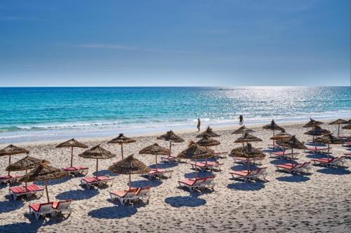 a group of chairs and umbrellas on a beach at Les Quatre Saisons Ex Baya Beach in Djerba