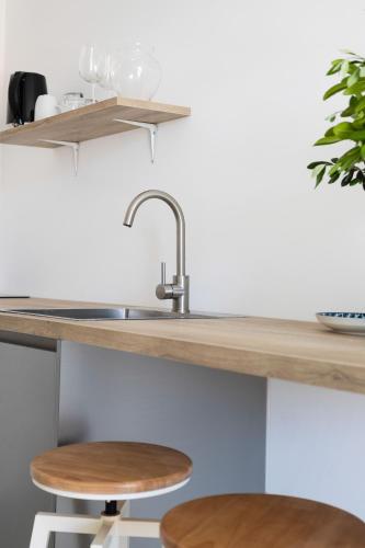 a kitchen counter with a sink and two stools at Poolside Architect Studios in Novalja
