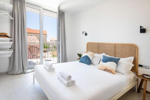 a bedroom with a white bed with a large window at Poolside Architect Studios in Novalja