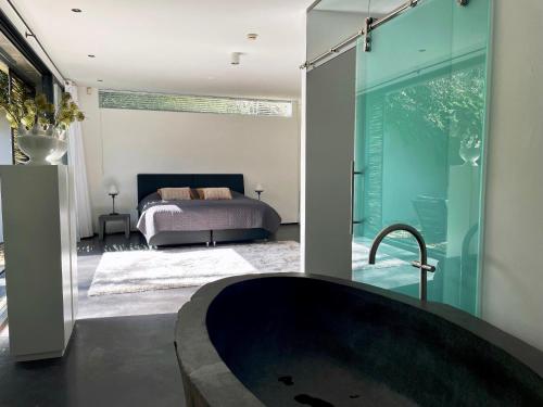 a bathroom with a bath tub and a bedroom at Betonnen Boshuis by Droomvilla in Oosterhout