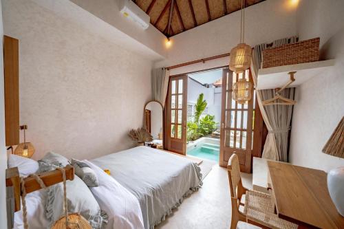 a bedroom with a bed and a table and a pool at Villa Taman & Villa Serai Kedungu in Tanah Lot