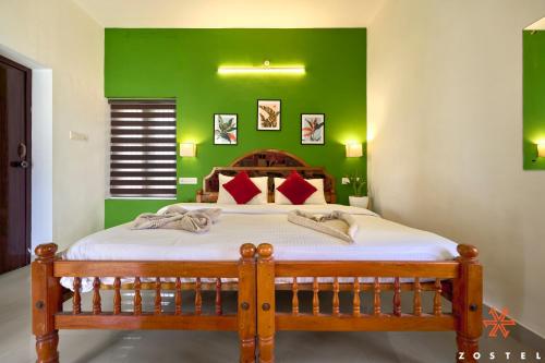 a bedroom with a wooden bed with a green wall at Zostel Varkala in Varkala
