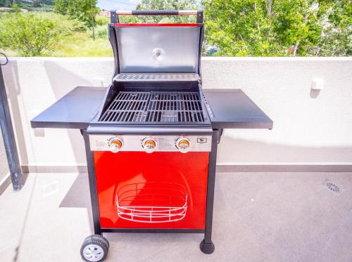 a bbq grill with a red top on a patio at Old Cinema Suites - Stylishly Decorated Retreat with Pool or Jacuzzi by the Sea in the Heart of Laganas Βy Villa Mana Gers in Laganas