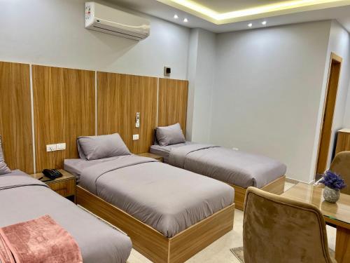 a room with three beds and a table and a desk at Elite hotel in Sheikh Zayed