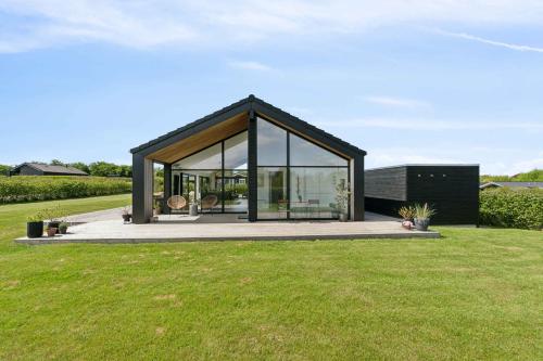 a black house with glass windows on a lawn at Modern Holiday Home On Beautiful Langeland in Humble