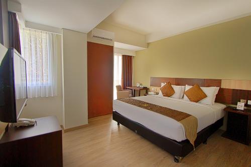 Habitación de hotel con cama grande y TV en Hotel Gunawangsa MERR en Surabaya