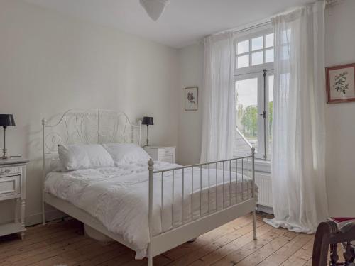 a white bedroom with a bed and a window at Romantische kamer nabij centrum in Eindhoven