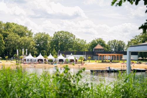 a group of tents on a beach next to a body of water at Vakantiepark BreeBronne in Maasbree