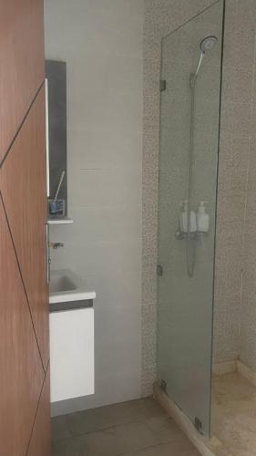 a bathroom with a glass shower with a sink at Appartement centre ville kenitra in Kenitra