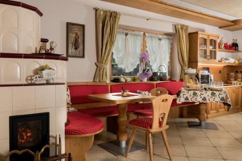 a living room with a table and a fireplace at Garnì Val de Grepa in Pozza di Fassa