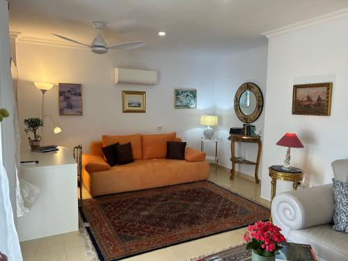 a living room with an orange couch and a mirror at Schönes Apartment - ruhig - Aussenpool in La Orotava