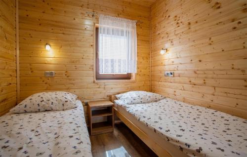 two beds in a wooden room with a window at Stunning Apartment In Ostrowite in Ostrowite