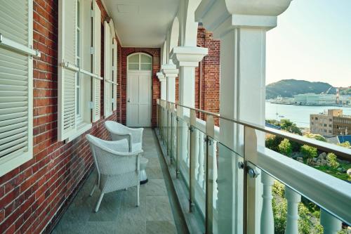 a balcony with two chairs and a view of the water at Hotel Indigo Nagasaki Glover Street by IHG in Nagasaki