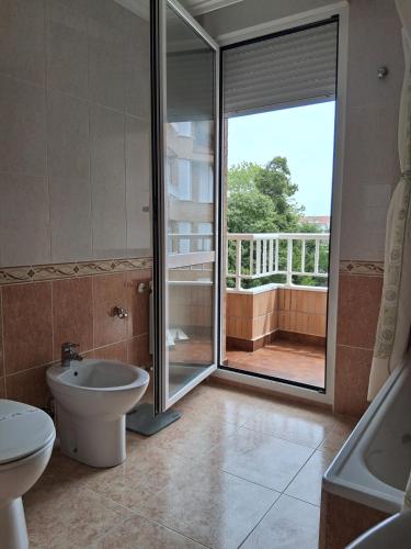 a bathroom with a toilet and a sink and a sliding glass door at R2R - Apartamento en Noja 2 dormitorios - C18A02 in Noja