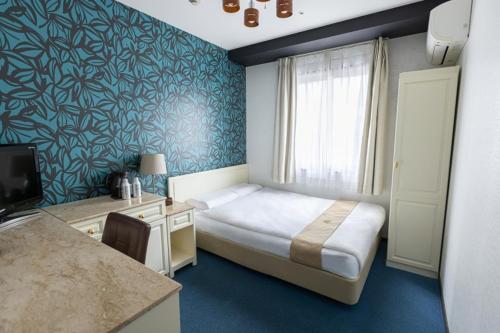 a bedroom with a bed and a desk with a television at New Osaka Hotel Shinsaibashi in Osaka