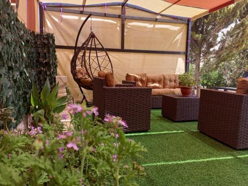 a patio with wicker chairs and a couch in a tent at بيت مزرعة ريفي in Madaba