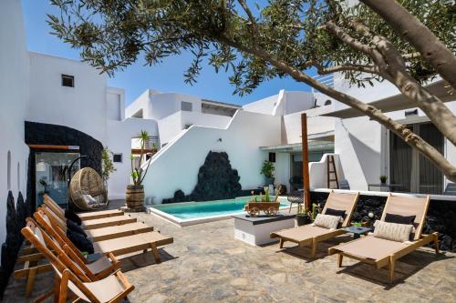 a courtyard with chairs and a swimming pool at Plastiras Rooms in Fira