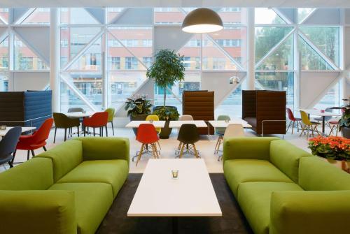 a lobby with green couches and tables and chairs at Scandic Victoria Tower in Stockholm