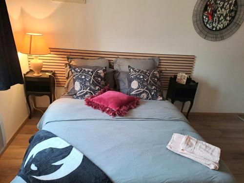 a bed with a pink pillow and pillows on it at Studio cosy in Villeneuve-sur-Lot