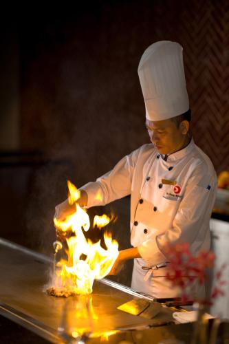 a chef cooking food on a grill with flames at Da Nang - Mikazuki Japanese Resorts & Spa in Da Nang