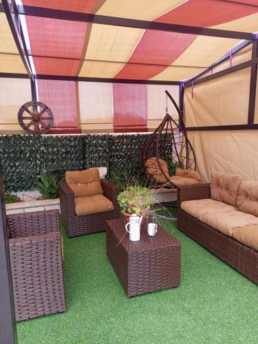 acovered patio with wicker chairs and tables in a tent at بيت مزرعة ريفي in Madaba