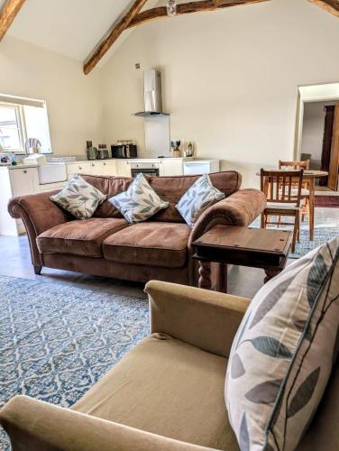 a living room with a brown couch and a table at Broomhill Barns in Minwear