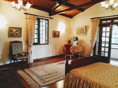Un dormitorio con una cama, un escritorio y ventanas. en Beautiful Villa with Pool and Amazing Garden, en Midlands Station