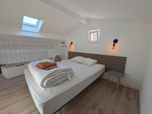 une chambre avec un lit avec des draps blancs et une fenêtre dans l'établissement Cyprès des cigales - Duplex meublé de tourisme, à Saint-Georges-dʼOrques