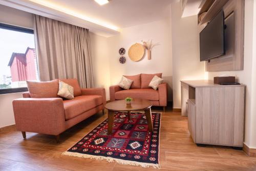 a living room with two couches and a tv at Sukoon Hotel Amman in Amman