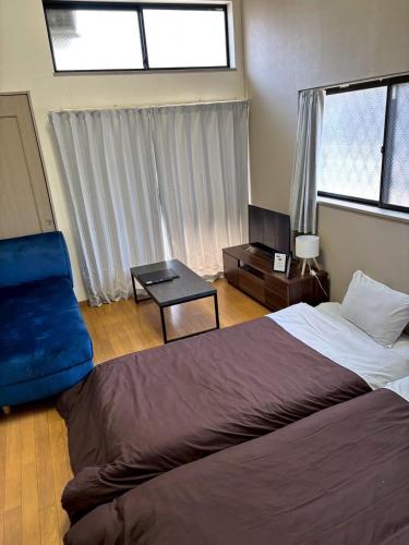 a bedroom with a bed and a chair and window at エスポアール新町103 in Kumamoto