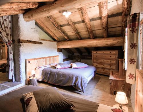 une chambre avec un lit dans une pièce avec des plafonds en bois dans l'établissement Chalet d'alpage de Savalin à 2000 mètres d'altitude au lac du Mont-Cenis, à Val Cenis