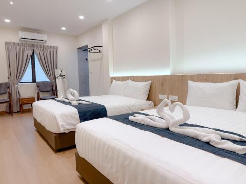 two swans are sitting on two beds in a hotel room at Resandau Stay Ipoh - Nearby Ipoh Town - Private Car Park and Lift - Whole unit & Coliving in Ipoh