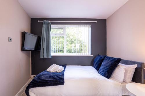 a bedroom with a bed with blue pillows and a window at Newly Refurbed 5 Bed House for Contractors, Families & Relocation- Cosely Wolverhampton in Coseley