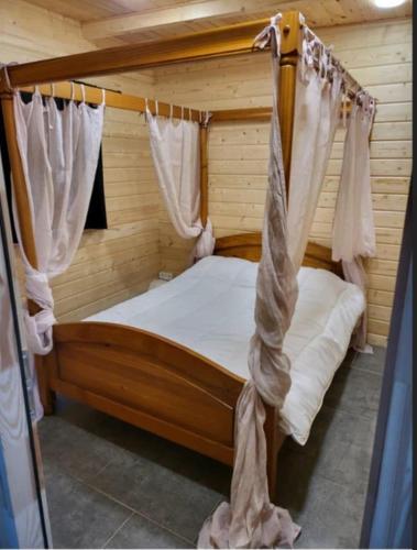 une chambre avec un lit à baldaquin avec rideaux dans l'établissement La Belle brune, avec jacuzzi, à Alincthun