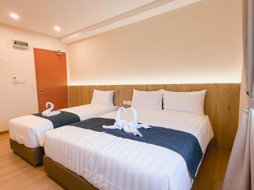 two beds in a hotel room with swans on them at Resandau Stay Ipoh - Nearby Ipoh Town - Private Car Park and Lift - Whole unit & Coliving in Ipoh