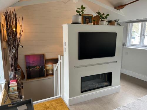 a living room with a tv and a fireplace at The Boathouse in Salcombe
