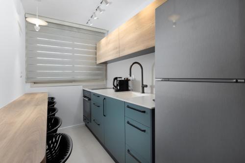 a kitchen with a sink and a refrigerator at אורה דירות אירוח - 6006 - דירת 2 חדרי שינה וסלון מעוצבת אדריכלית במרחק הליכה מהים in Eilat