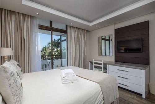 a bedroom with a large white bed with a television at The Breakers 310 in Durban