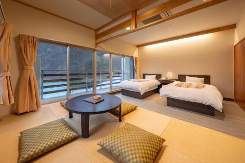 a room with two beds and a table and a window at Ashionoyado Kajika in Nikko