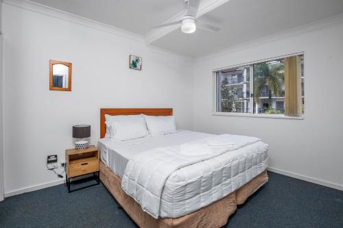 a white bedroom with a bed and a window at Blue Water Bay Luxury Villas - Southport in Gold Coast