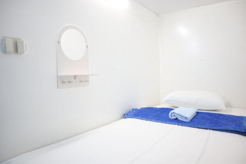 a bed with a blue blanket and a mirror on it at TAMU CAPSULE HOTEL in Yogyakarta