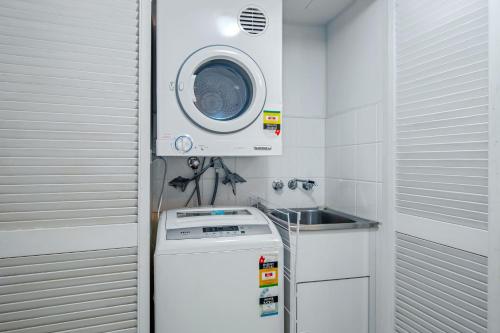 a small kitchen with a washing machine and a sink at Blue Water Bay Luxury Villas - Southport in Gold Coast