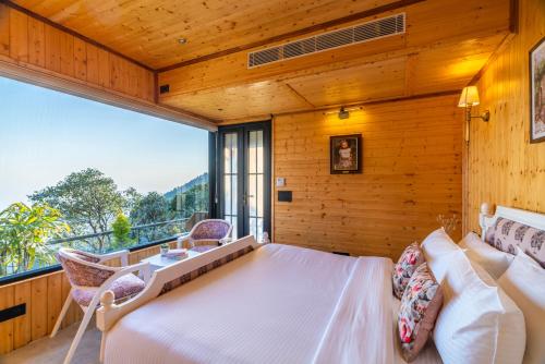 a bedroom with a large bed and a balcony at The English Country House in Mussoorie