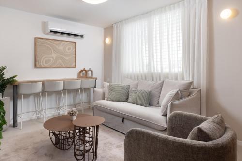 a living room with a couch and a table at אורה דירות אירוח - 6006 - דירת 2 חדרי שינה וסלון מעוצבת אדריכלית במרחק הליכה מהים in Eilat