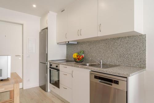 a kitchen with white cabinets and a sink at HostWise - Modern & Bright Studio in Porto